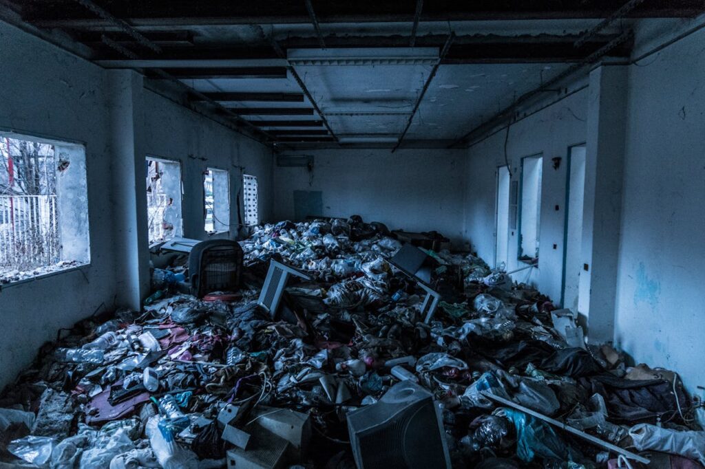 Interior of an abandoned building cluttered with trash and debris, creating a scene of decay and neglect.